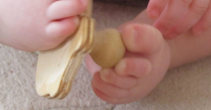 Photo of an infant picking up a puzzle piece with her toes.