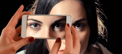 Self portrait combining an image of a woman's face and a portion of that same face on a smartphone display