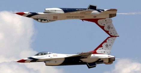 Photo of two fighter jets flying in formation, one inverted directly above the other.