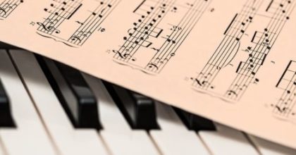 Photo of piano keyboard with sheet music laid on top