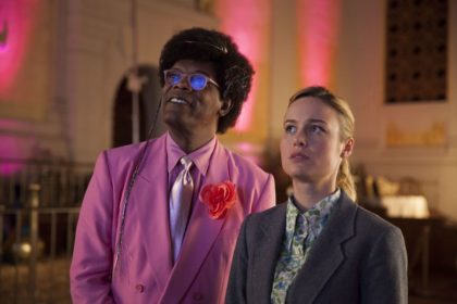 Frame from Unicorn Store of Samuel L Jackson and Brie Larson standing side by side, looking up to the left. They are in the abandoned church set.