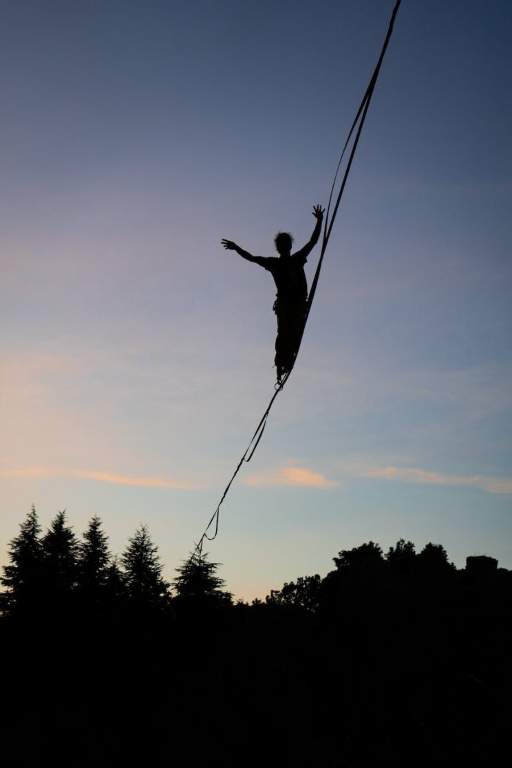 silhouette of a person balancing on a tightrope at dusk