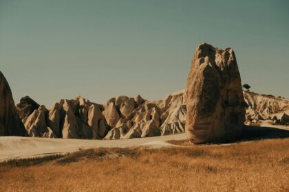 photograph of boulder in foreground and rocky hills in background; the boulder appears taller because of foreshortening and the angle of the photo